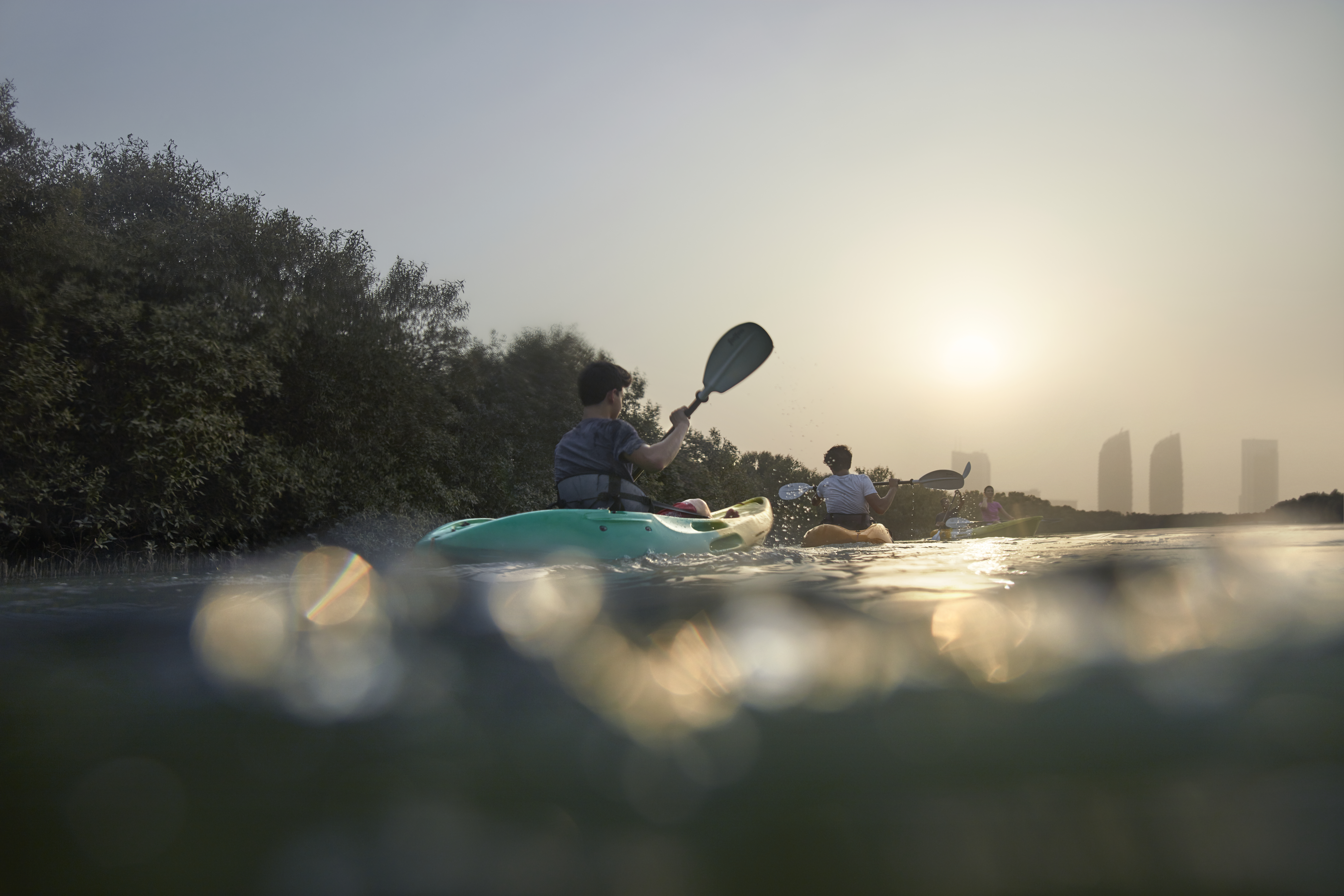 رجال يقومون بركوب قوارب الكاياك بين أشجار القرم في أبوظبي