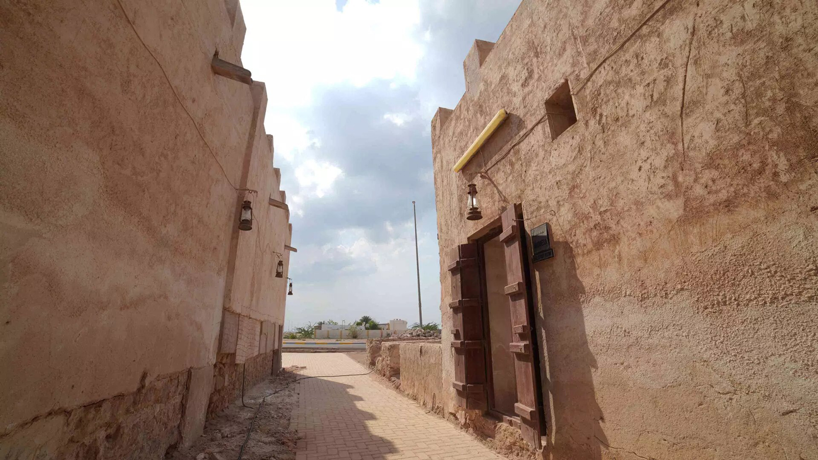 Dalma Island heritage and history: Path beside two buildings, lush trees, and blue sky
