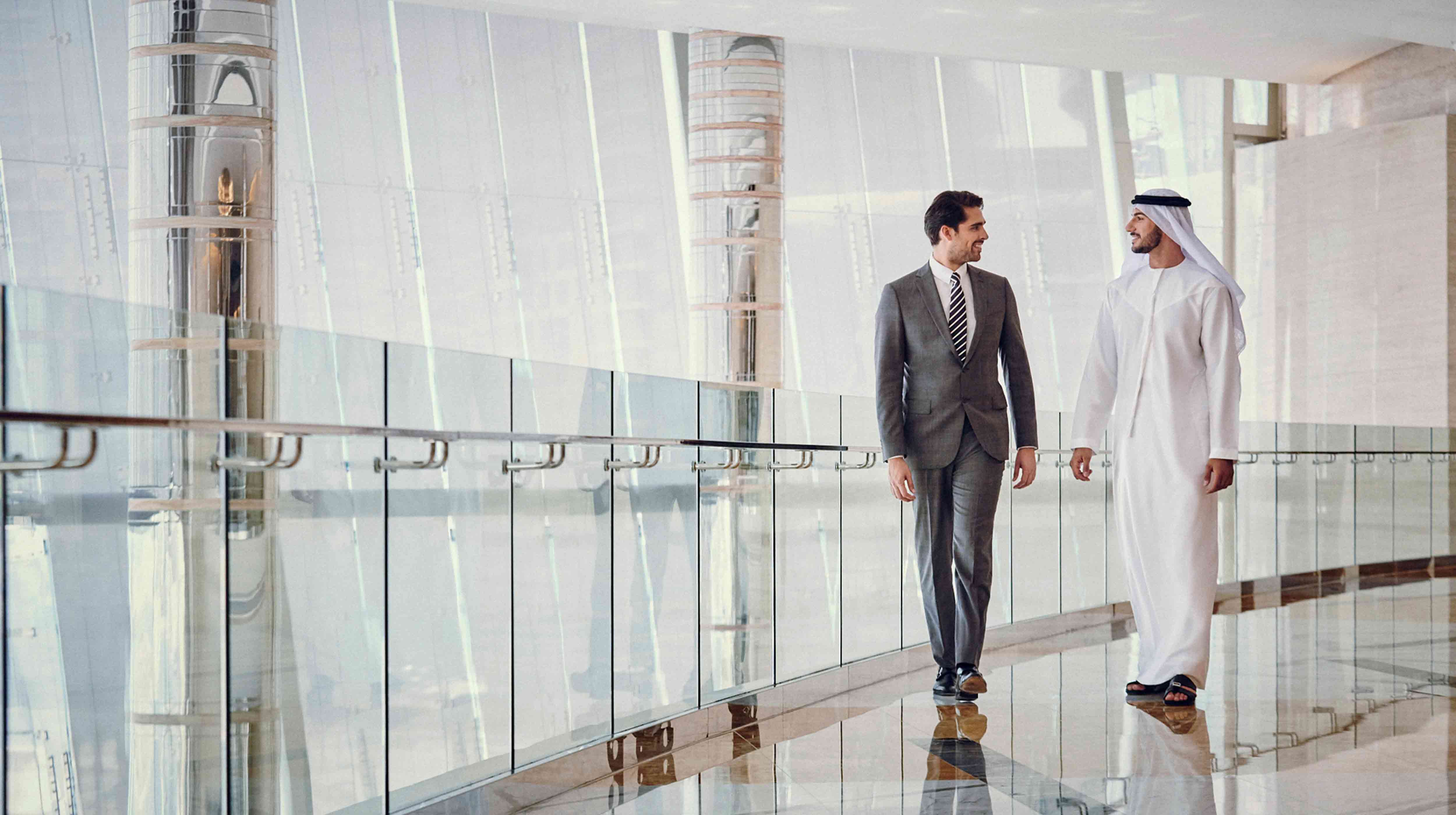 2 business men smiling and walking in the Abu Dhabi convention exhibition bureau