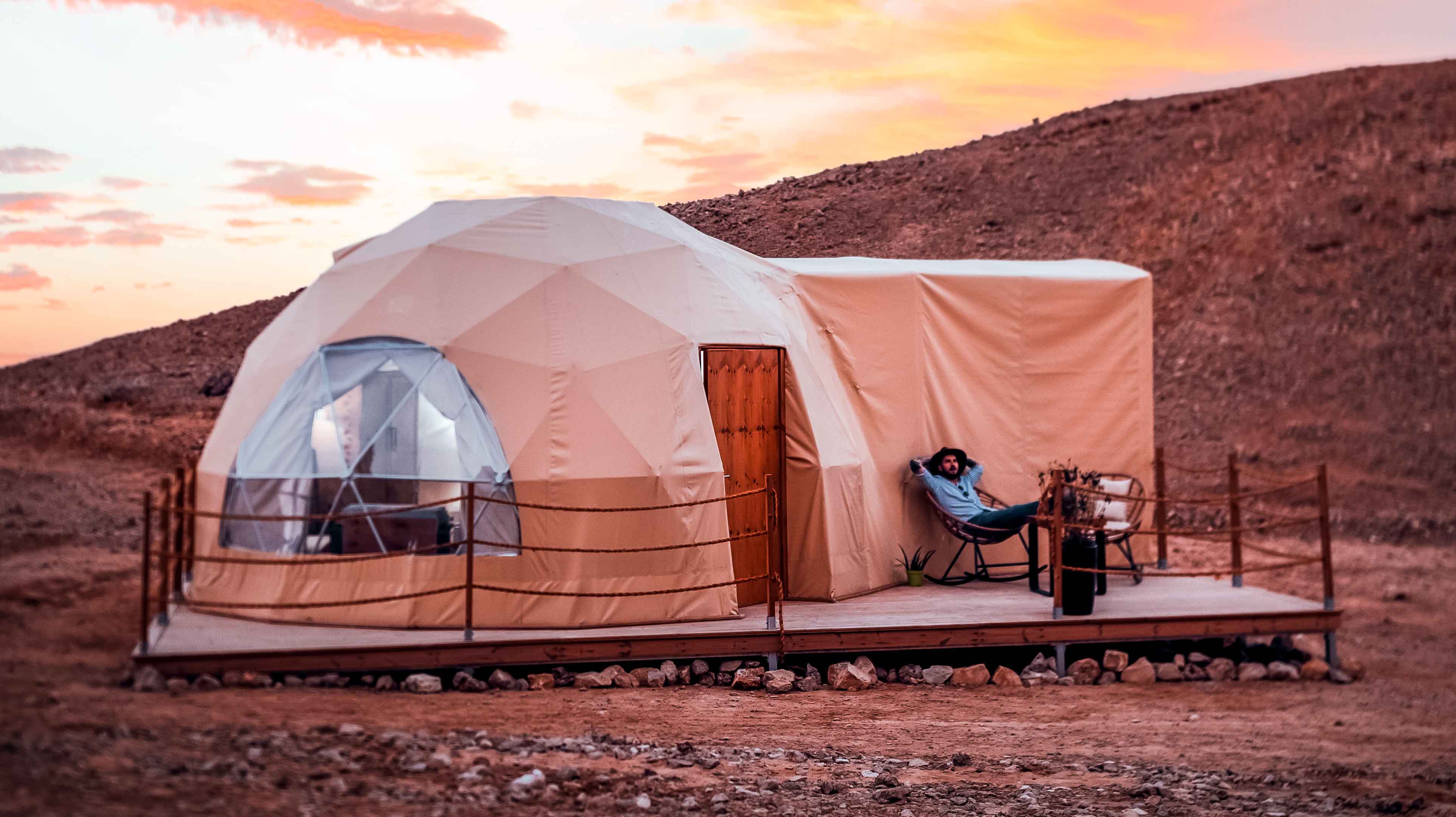 Man sitting outside a glamping pod at Jebel Hafit 