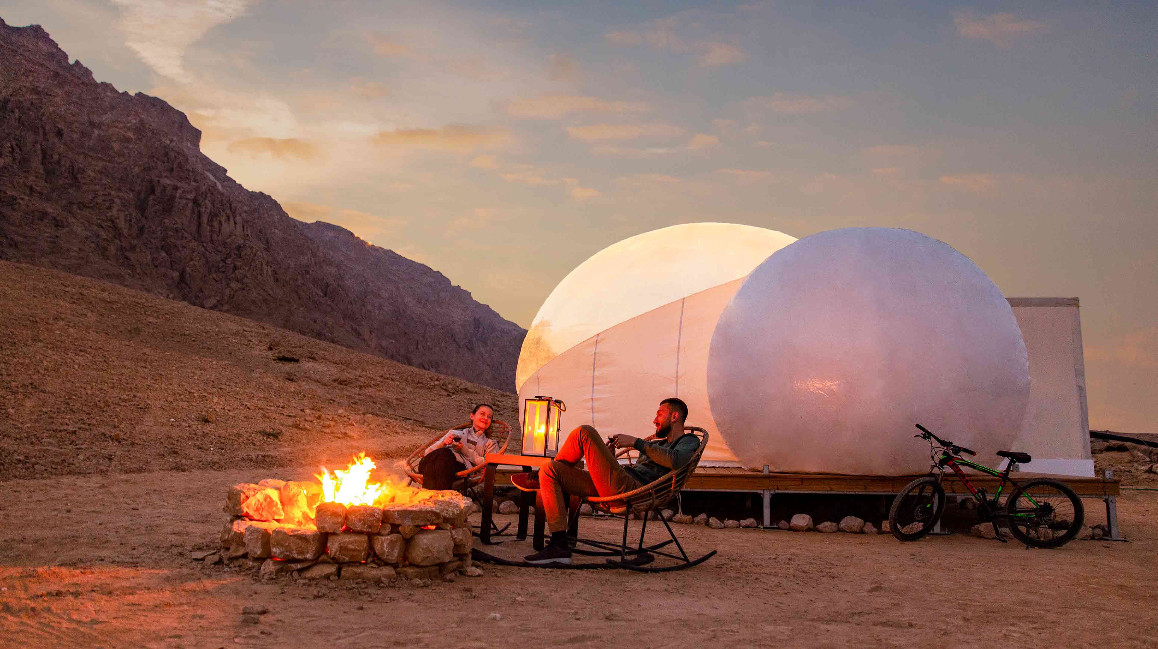 A couple sitting by a campfire at Jebel Hafit