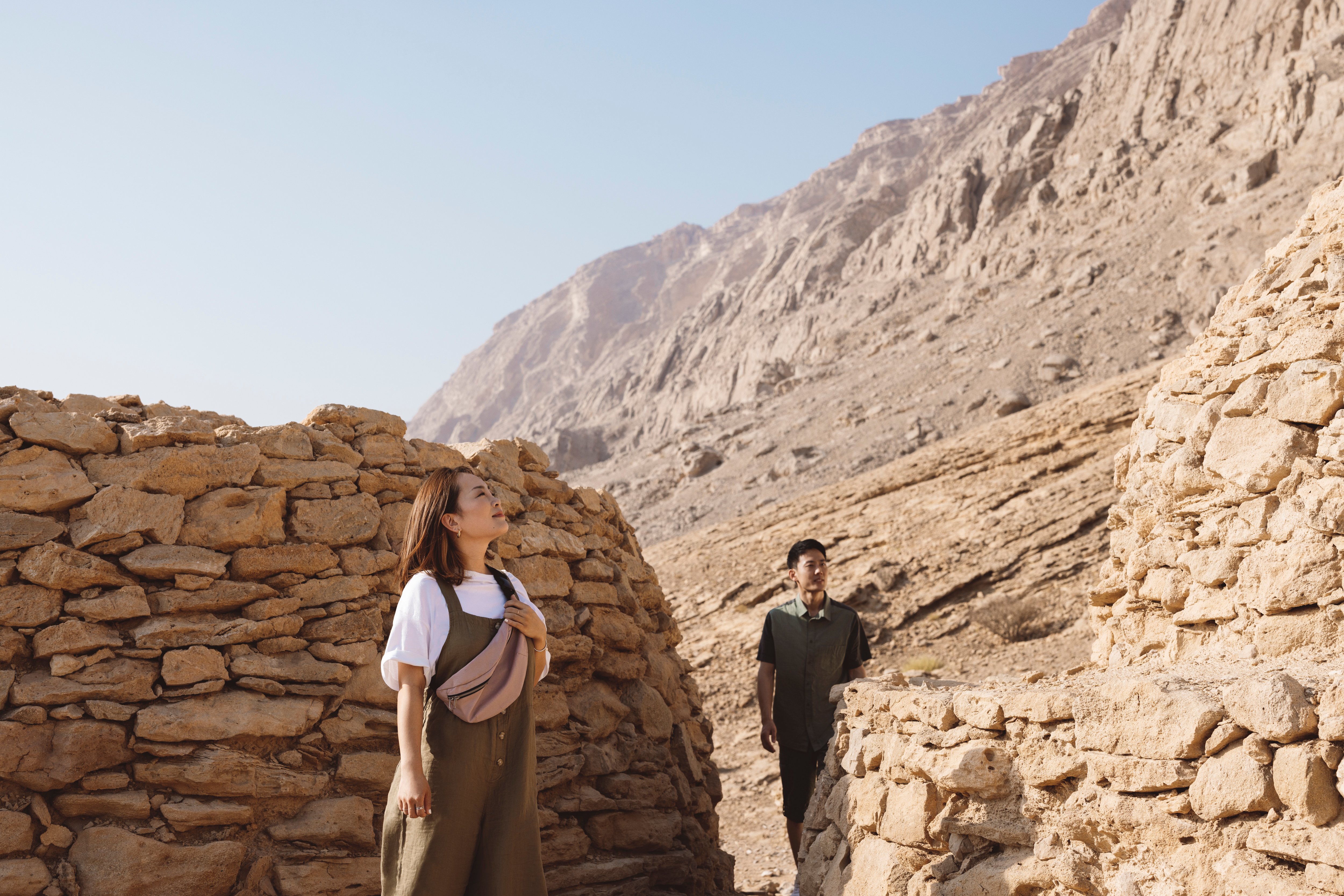 Two people exploring ancient stone tombs at Jebel Hafit in Abu Dhabi's rugged mountains.