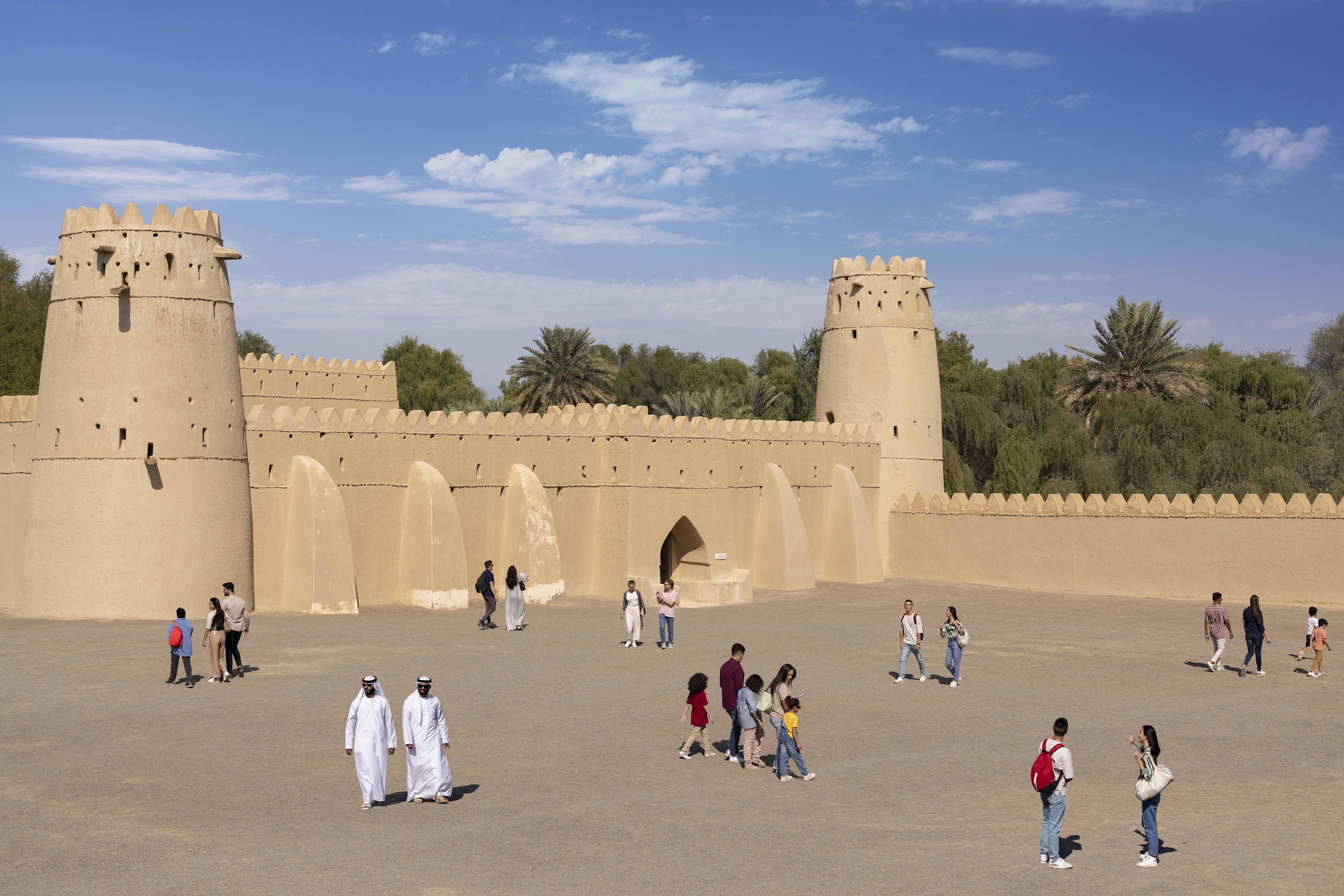 Visitors exploring Al Jahili Fort in Al Ain, Abu Dhabi, under a clear blue sky.