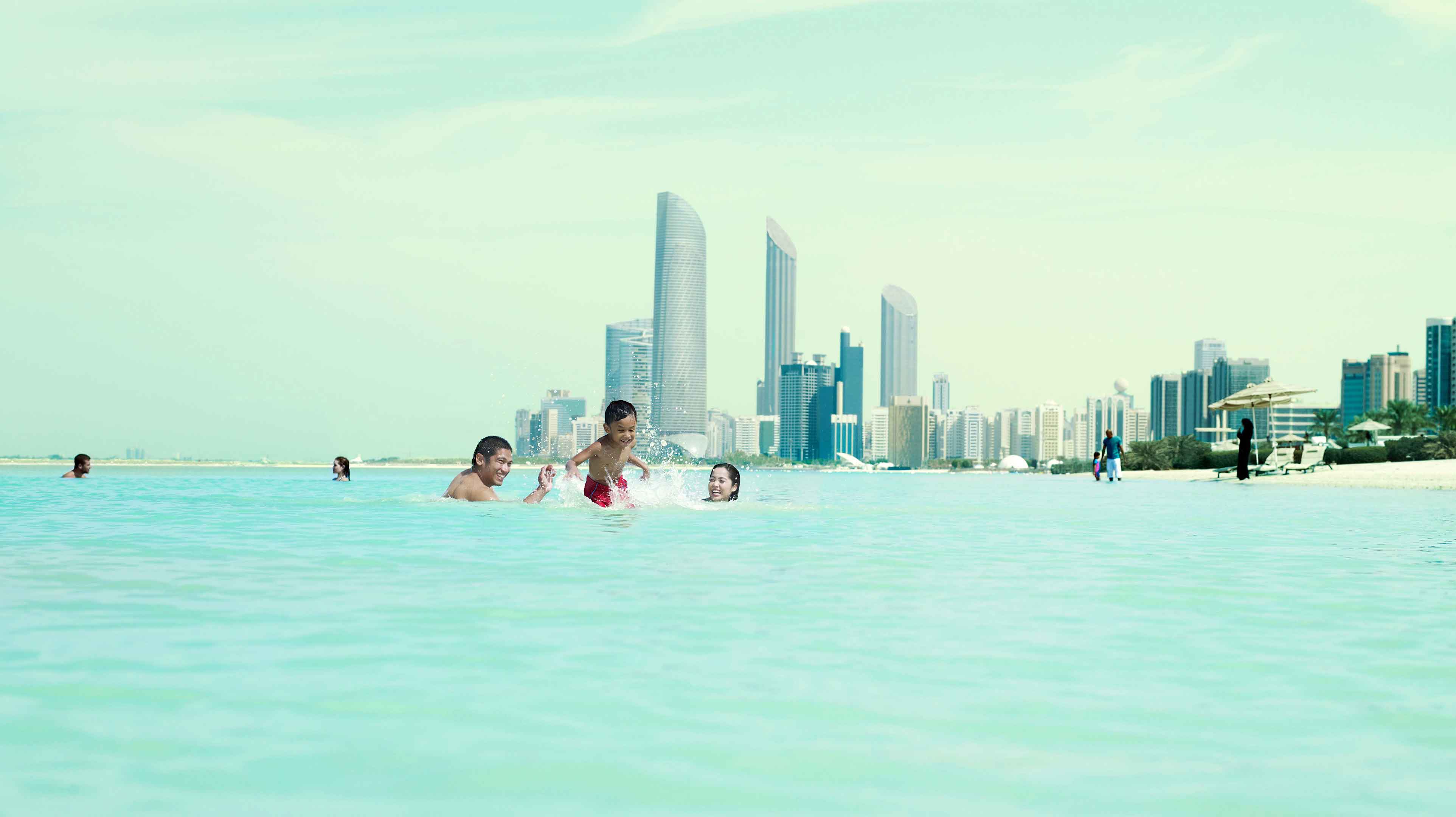 Familia bañándose en el mar en playa de Corniche de Abu Dhabi