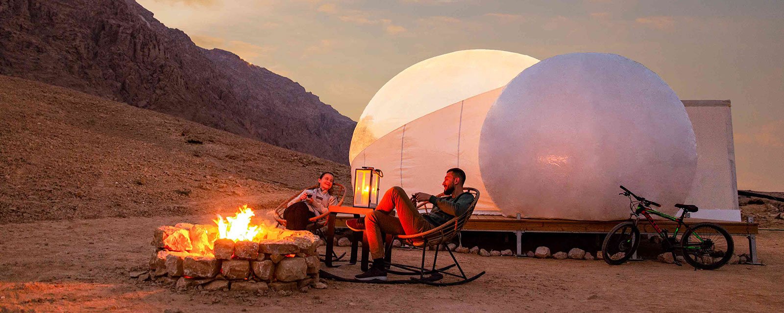 Romantische Szene am Lagerfeuer im Jebel Hafeet Desert Park bei Sonnenuntergang