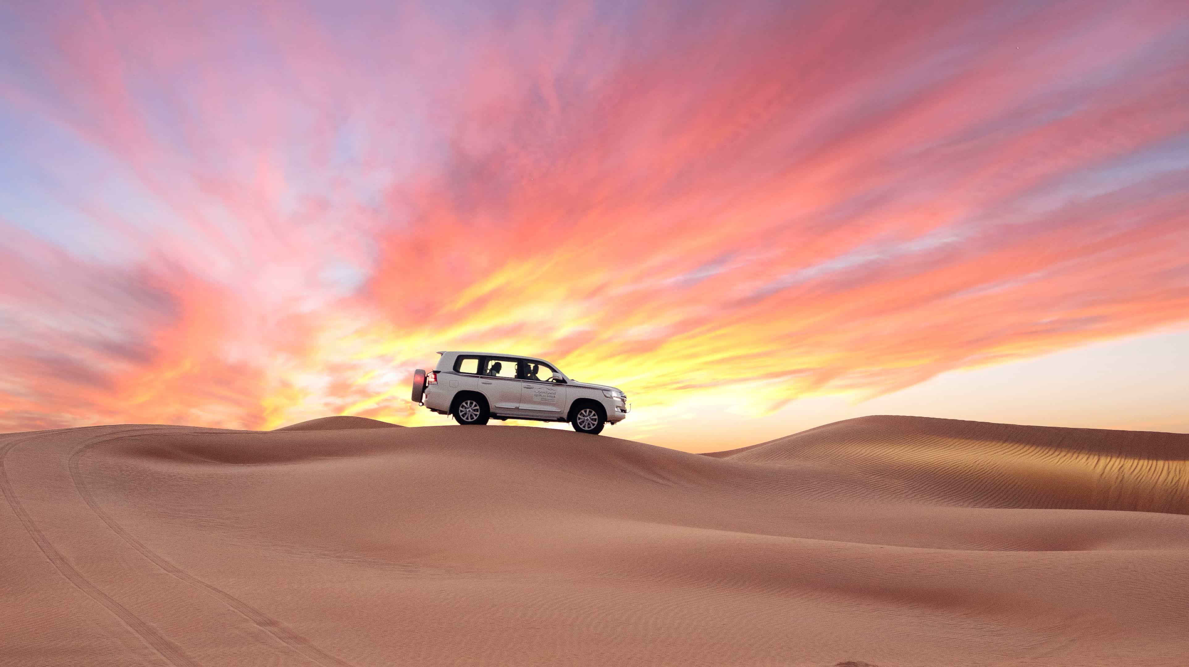  Lors d’un safari dans le désert, un 4x4 sillonne les dunes au coucher du soleil : une aventure exaltante au cœur des paysages dorés d’Abu Dhabi.