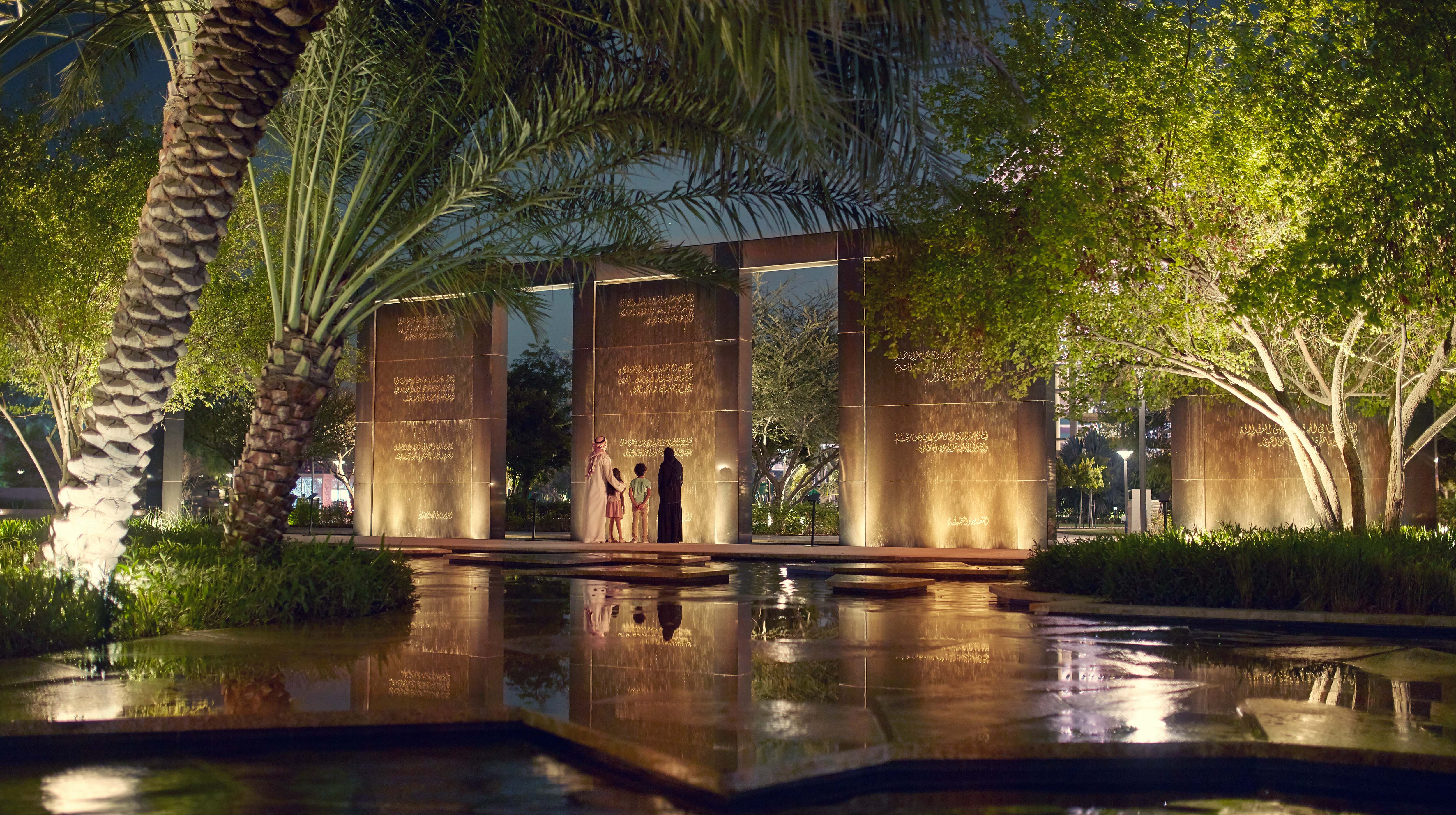 Emirati family standing and reading inscriptions on a wall at Umm Al Emarat Park