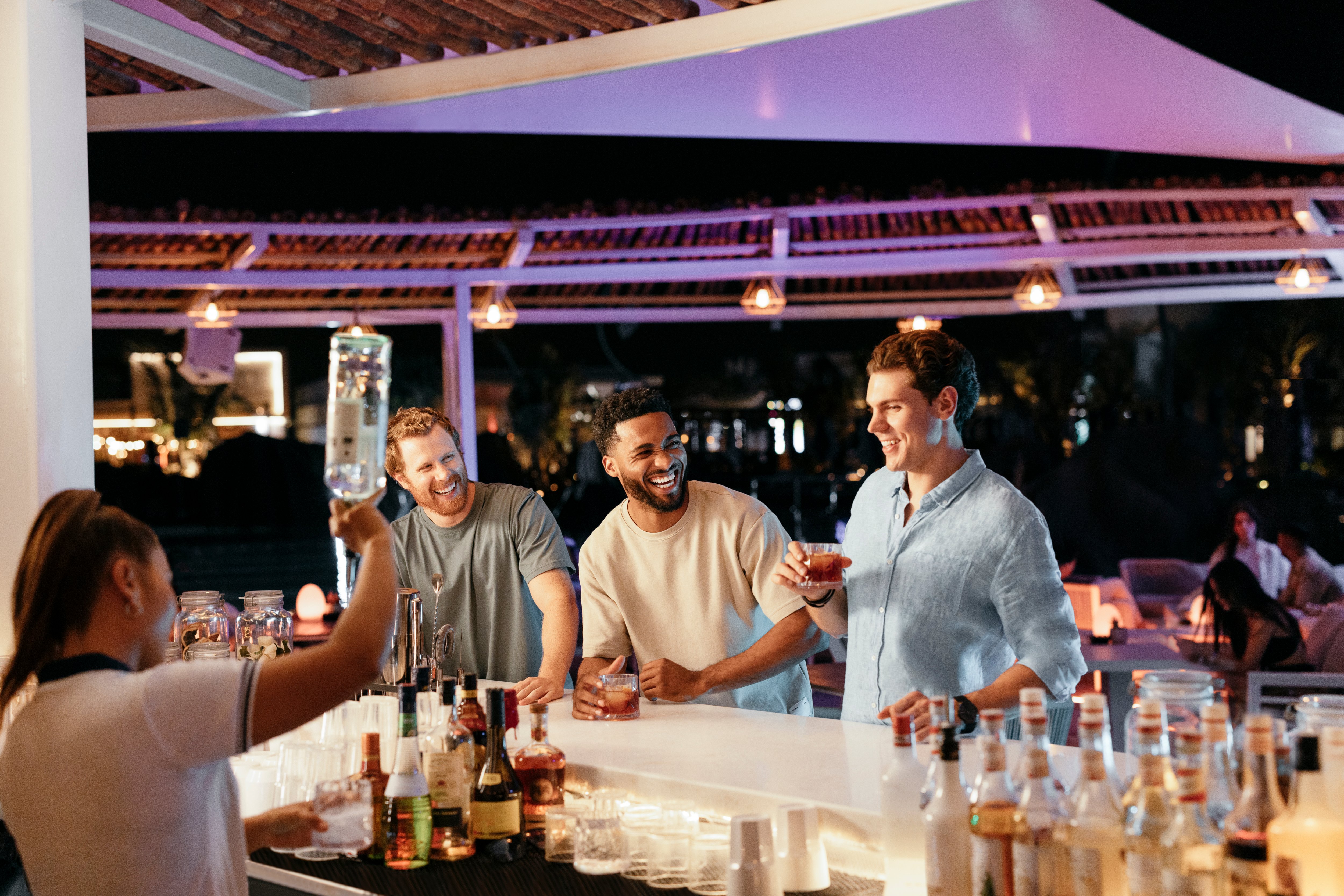 Friends enjoying cocktails at a stylish rooftop bar in Abu Dhabi, with a lively nighttime ambiance.