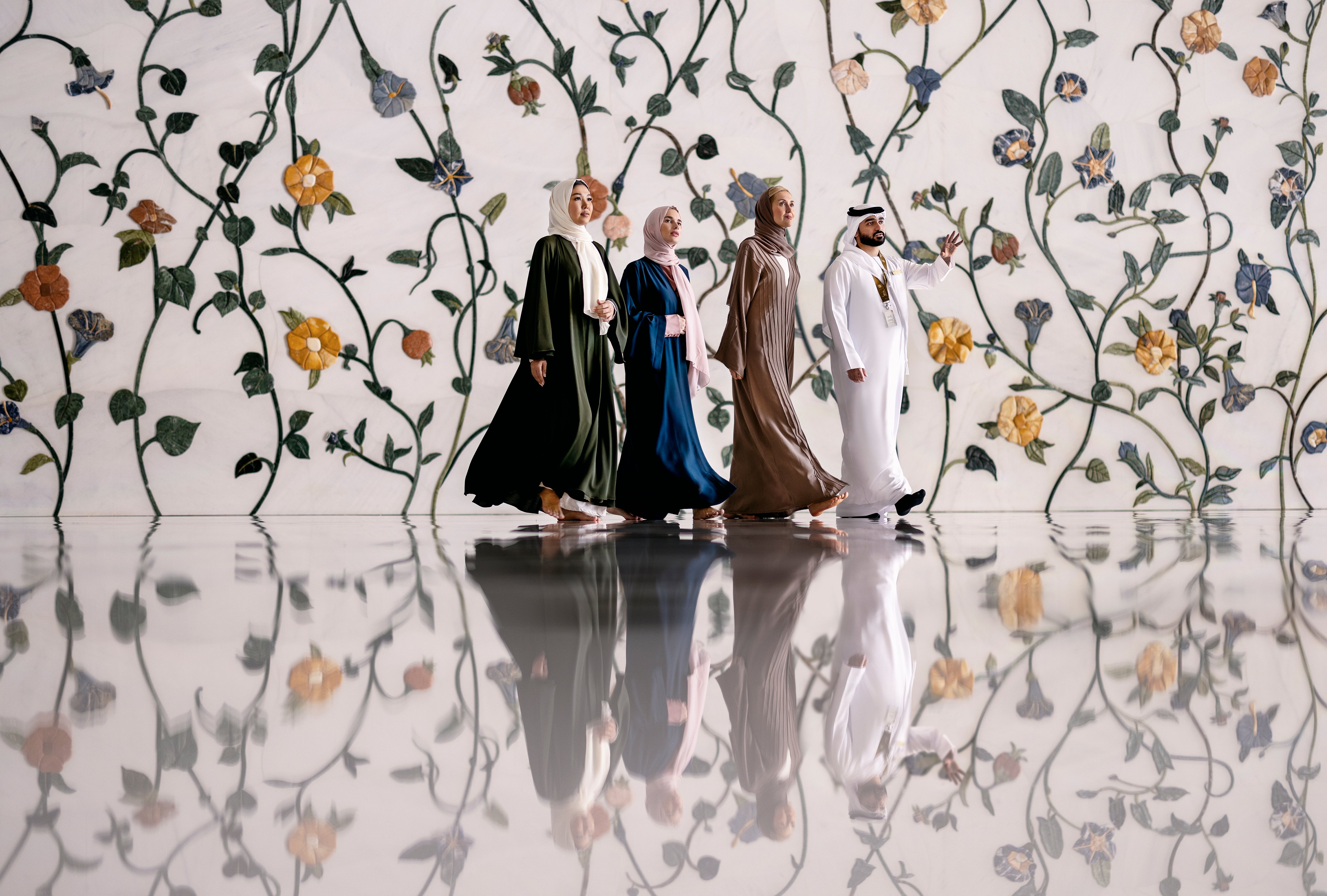 Three women walking with a local guide inside the beautiful Sheikh Zayed Grand Mosque interior