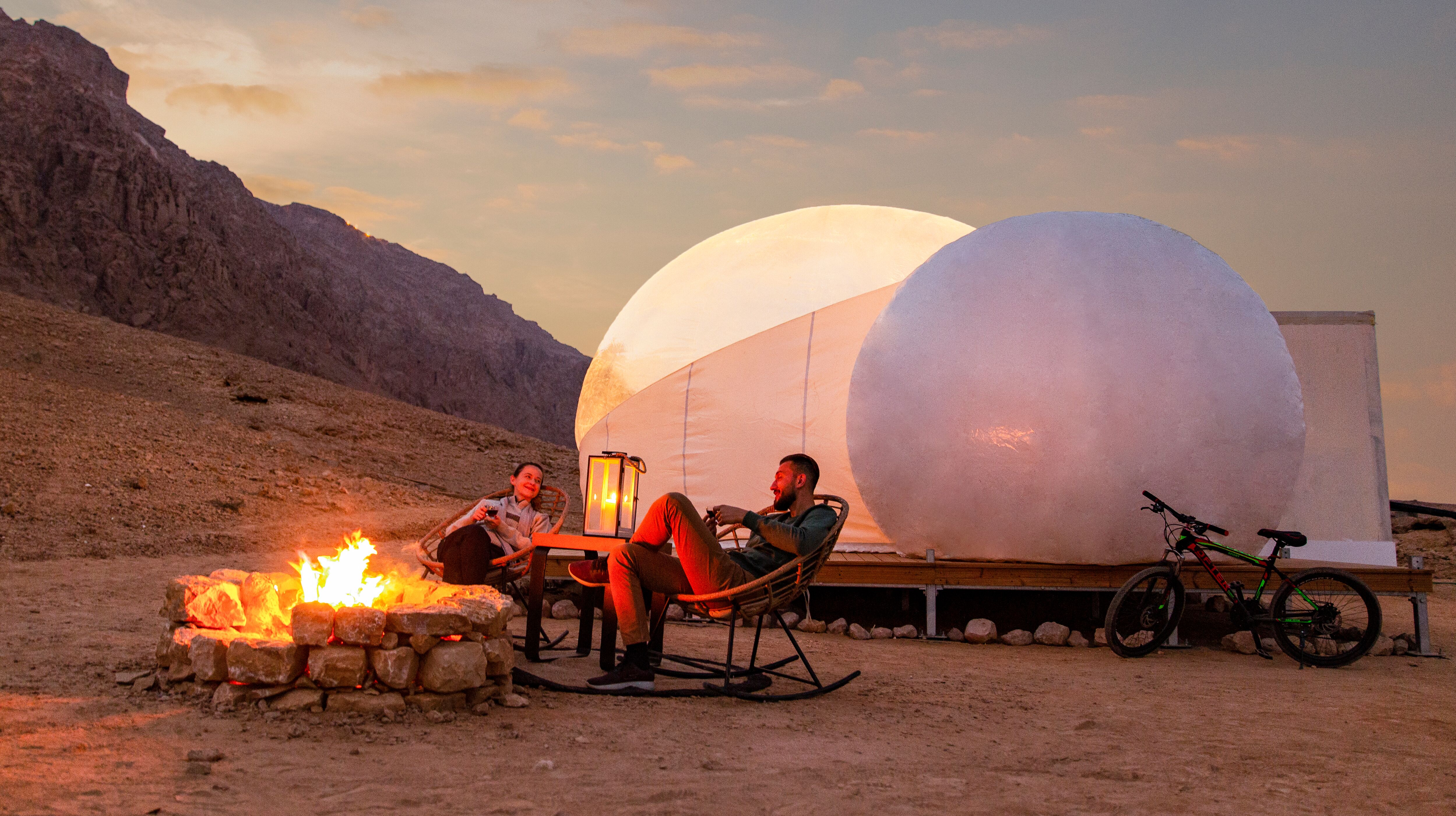 A couple sitting by a campfire at Jebel Hafit