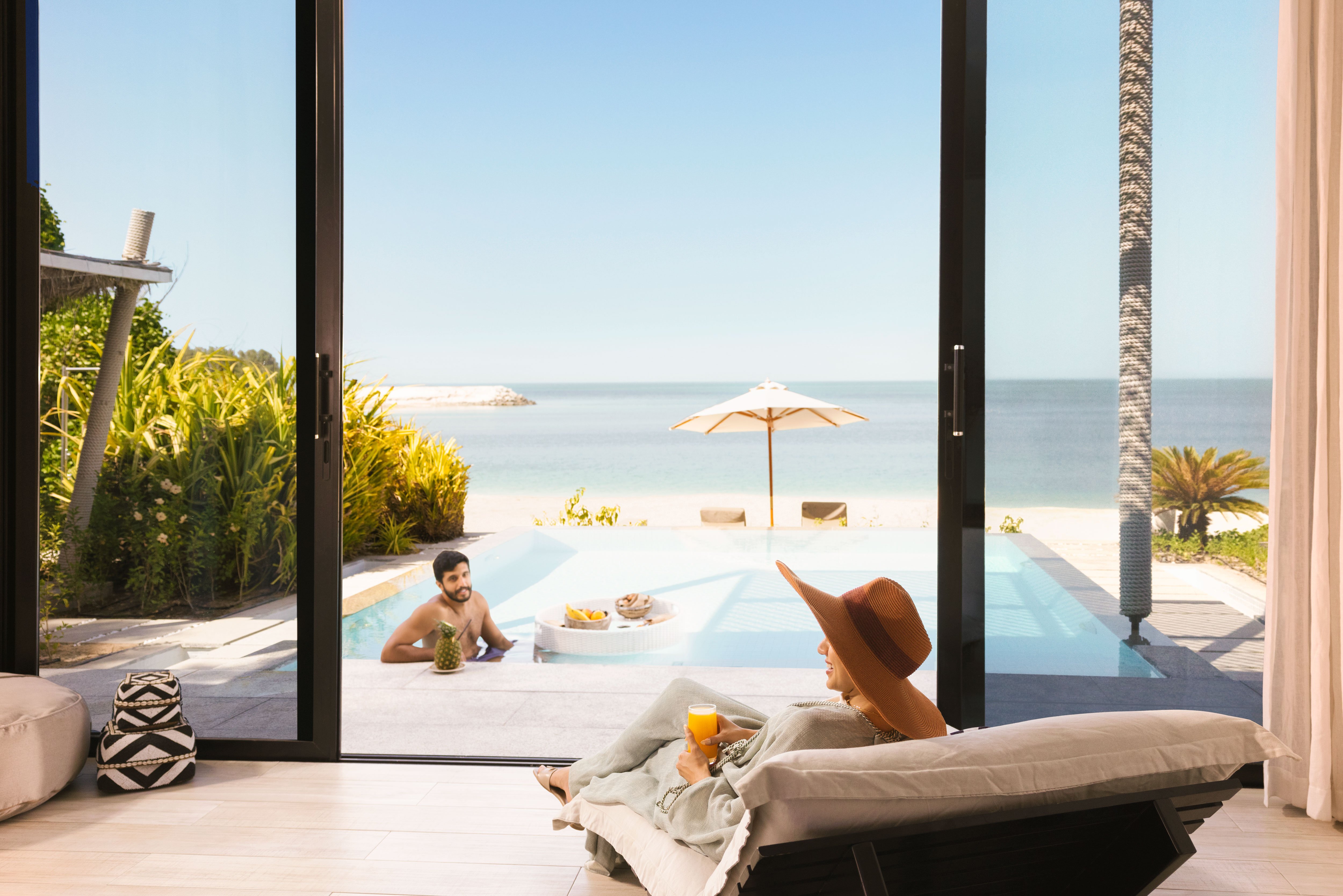 Couple relaxing by a pool adjacent to the sea on Nurai Island