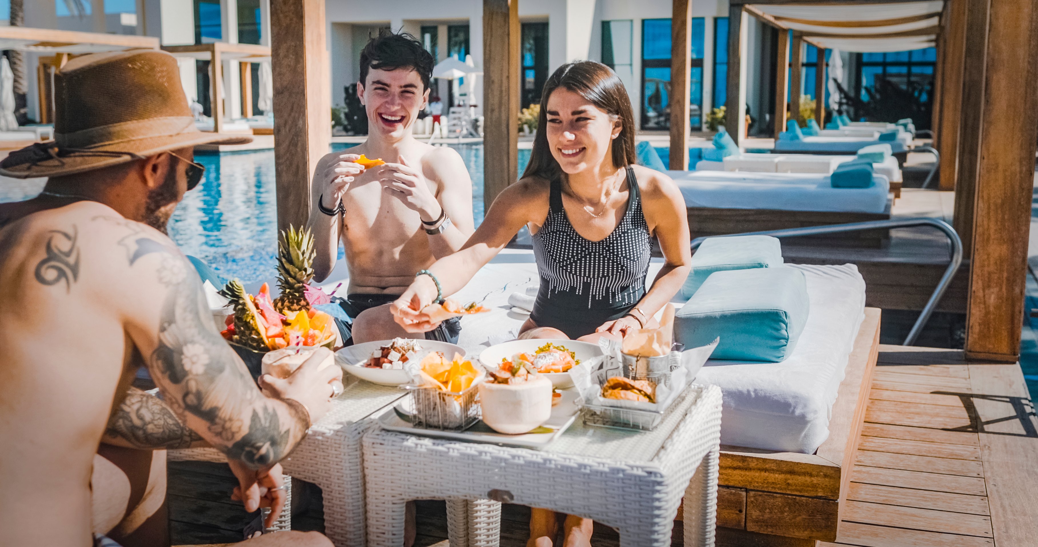 Three Western friends smiling at each other and eating in Saadiyat Island