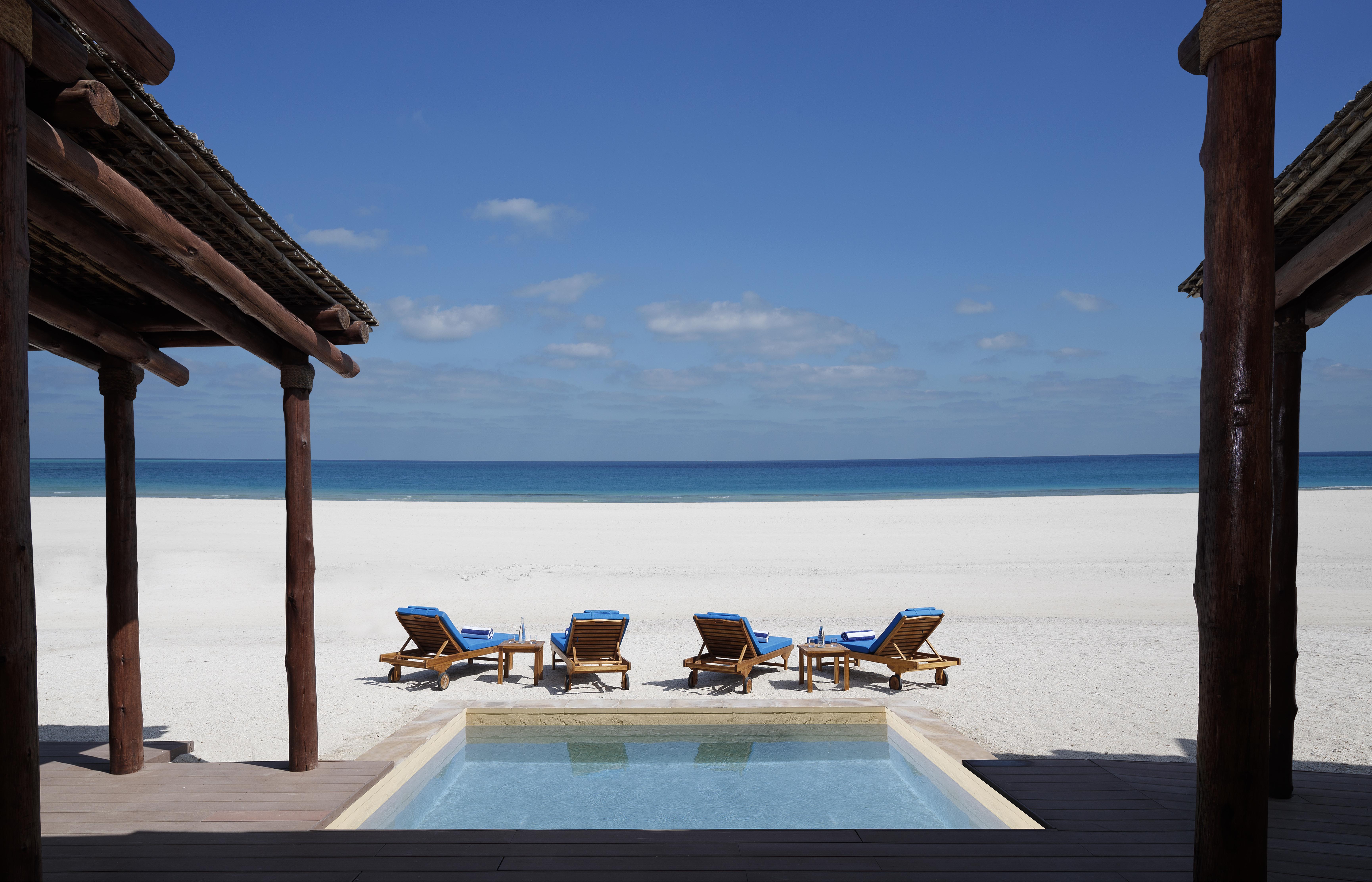 Blue sunbeds in front of a swimming pool near a beach on Sir Bani Yas Island