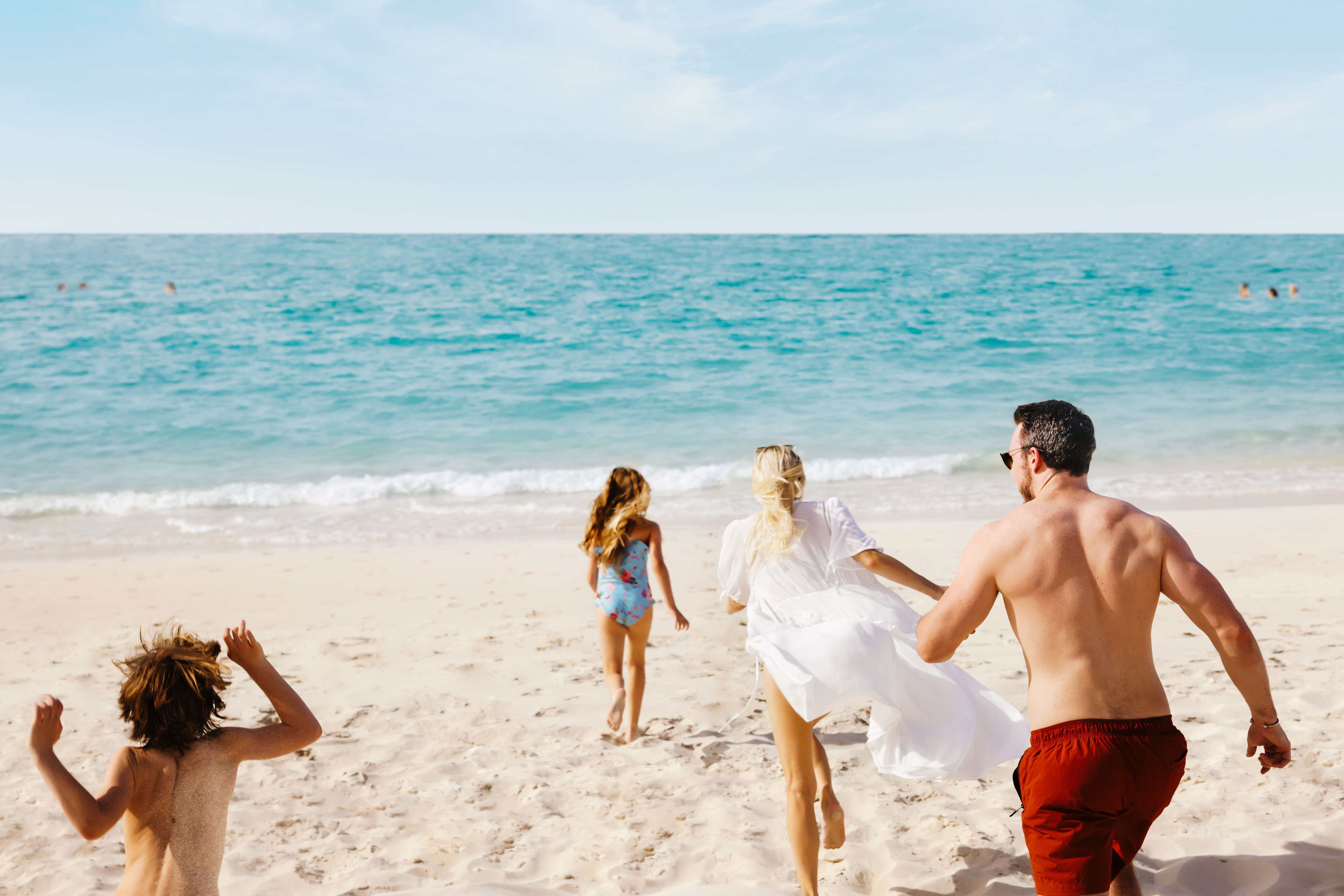 Family of four running towards the sea water in Abu Dhabi