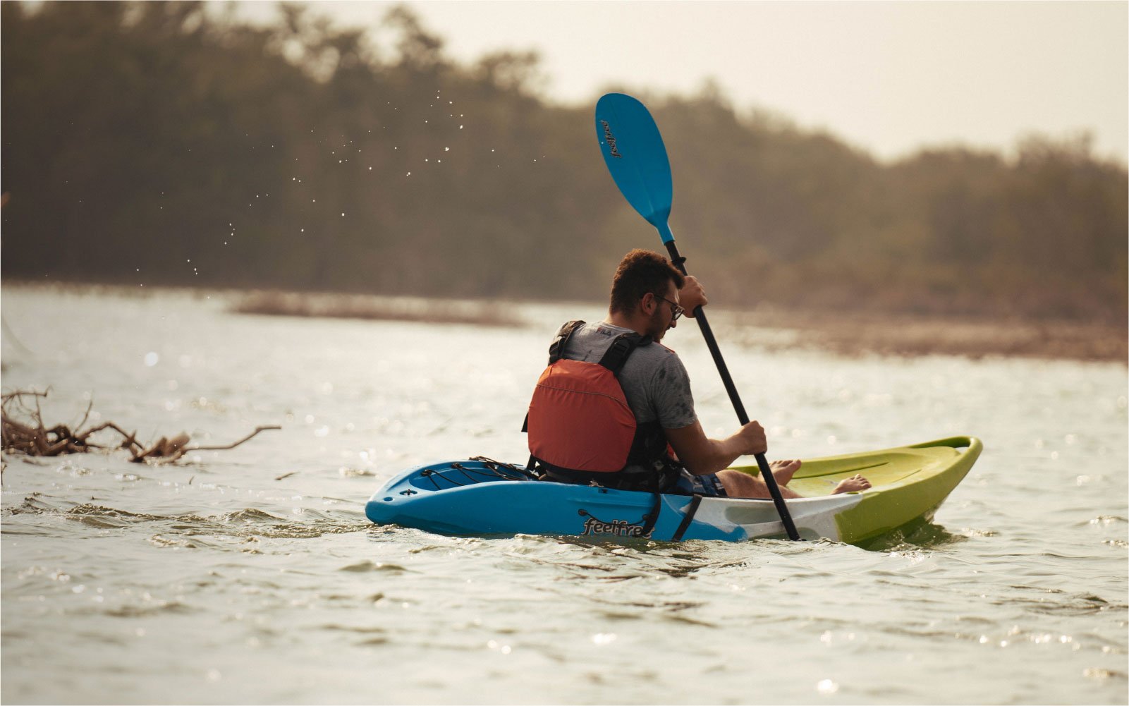 Man kayaking on a blue and green kayak in the middle of the water in Abu Dhabi